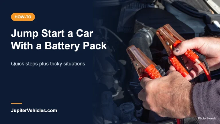 Person holding jumper clamps in front of a car engine